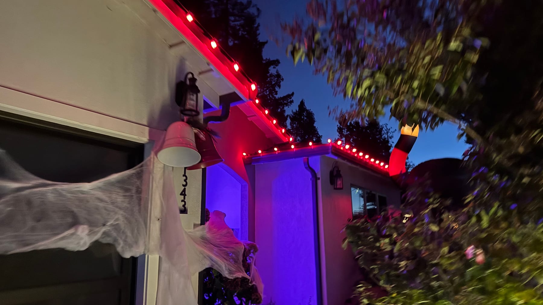 A closer view of red and purple Halloween lights along a home’s entry and roof