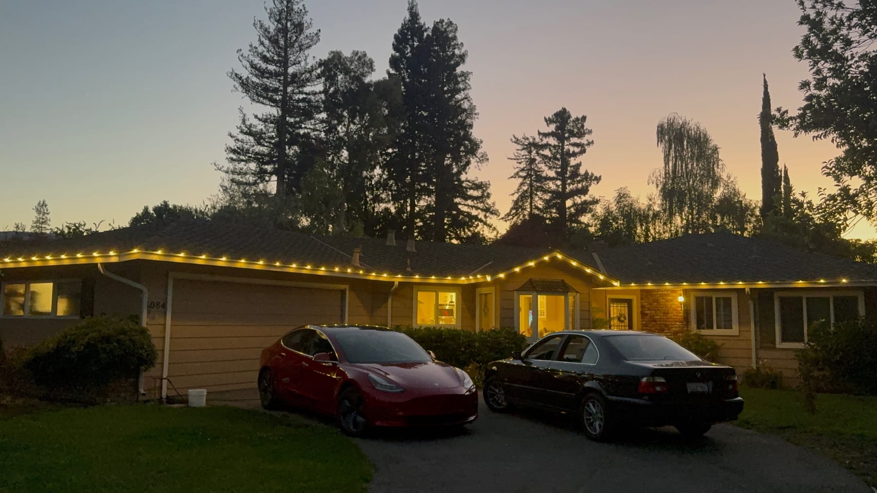 Warm white lights custom fitted along a single-story home’s roofline at sunset