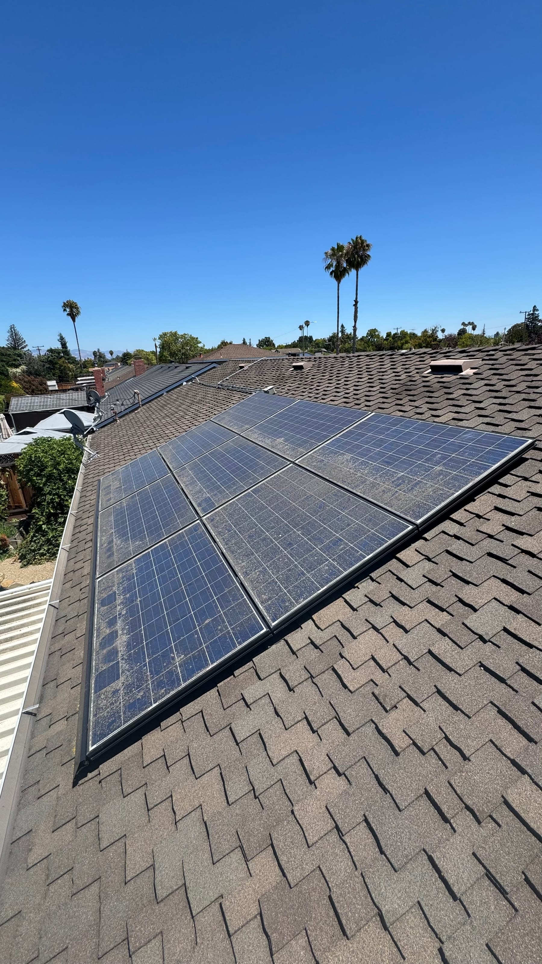 Dusty solar panels before cleaning on a tiled rooftop