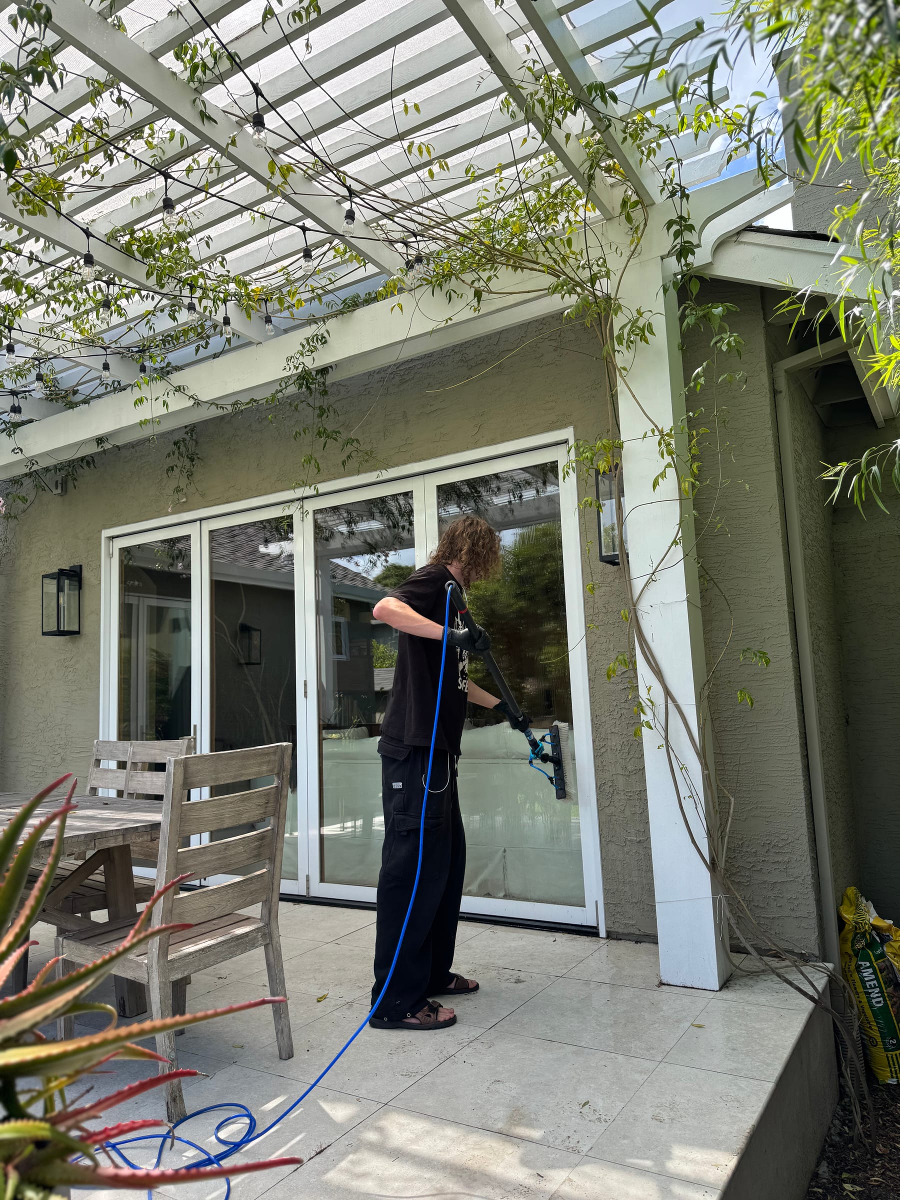 A Bright Blast Teens worker washing windows below a pergola